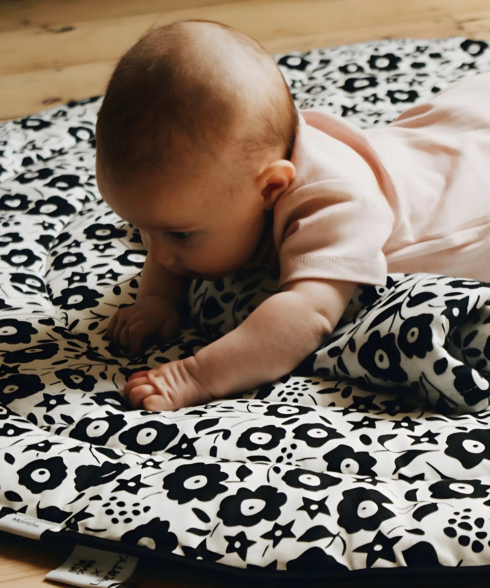 Baby crawling on top of the GOTS organic cotton Etta Loves x Liberty sensory reversible playmat showing the Fairford shadow design