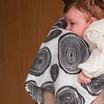 An adult holding a baby with the Etta Loves muslin square in plan print on the shoulder