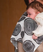An adult holding a baby with the Etta Loves muslin square in plan print on the shoulder