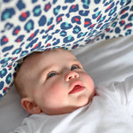 A baby looking at the visually stimulating Etta Loves colourful leopard print muslin square.