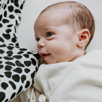 A tiny baby looking at the Etta Loves dalmatian organic cotton muslin square.