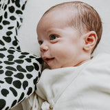 A tiny baby looking at the Etta Loves dalmatian organic cotton muslin square.