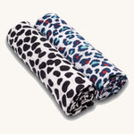 Two Etta Loves organic cotton muslin swaddle squares, one has a monochrome dalmatian print for babies under 4 months old, and another has a colourful leopard print to support the visual development of babies 5 months +.