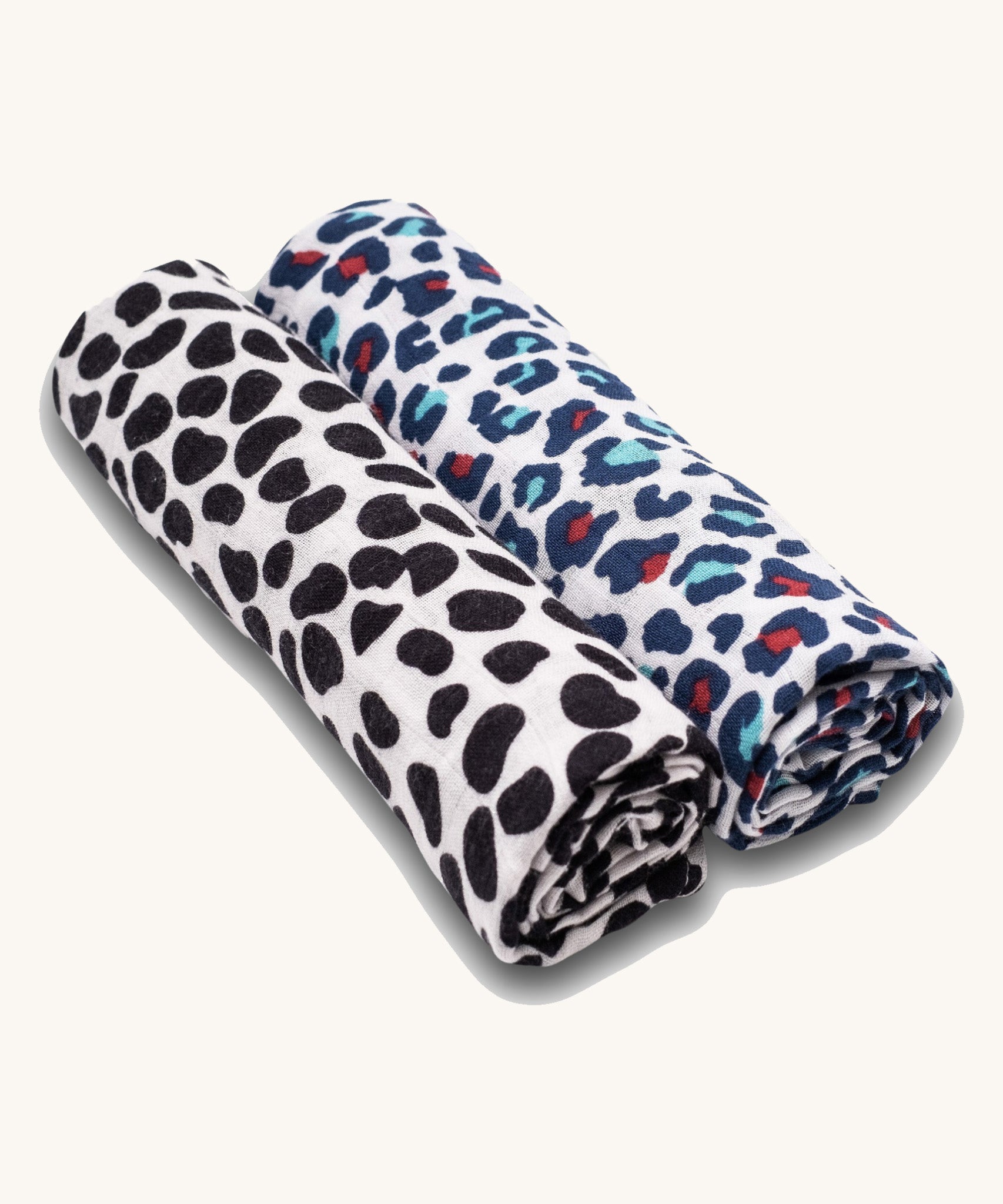 Two Etta Loves organic cotton muslin swaddle squares, one has a monochrome dalmatian print for babies under 4 months old, and another has a colourful leopard print to support the visual development of babies 5 months +.