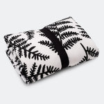 A baby looking and enjoying and looking at the black and white Fern side of the Etta Loves Reversible Organic Cotton Baby Play Mat - Plant Print 