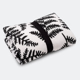 A baby looking and enjoying and looking at the black and white Fern side of the Etta Loves Reversible Organic Cotton Baby Play Mat - Plant Print 