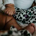 A baby looking up at the purple and green Leopard spot print on the Etta Loves Organic Cotton Baby Muslin Squares 3 Pack - Leopard