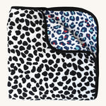 The Etta Loves Reversible Organic Cotton Muslin Blanket - Animal Print, with a fun, black, spotty Dalmatian print on one side, and a colourful Leopard print on the other