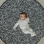 A baby lying down and looking at the black