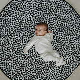 A baby lying down and looking at the black