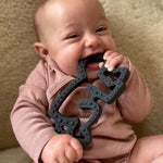 A baby chewing and plaing with the Etta Loves X Keith Haring Natural Rubber Sensory Teether - Baby