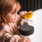 A toddler standing next to a bath with the Etta loves sensory bath toys on the rim