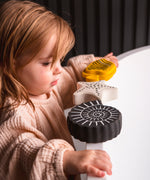 A toddler standing next to a bath with the Etta loves sensory bath toys on the rim
