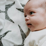 A toddler surrounded with the Etta Loves Organic Cotton Muslin Squares 3 Pack - Animal Print