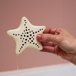 A adult hand holding the starfish bath toy from the Etta Loves sensory bath toy set