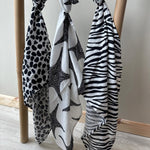 Three Etta Loves XL Muslin clothes tied to a wooden bamboo ladder in Leopard Print