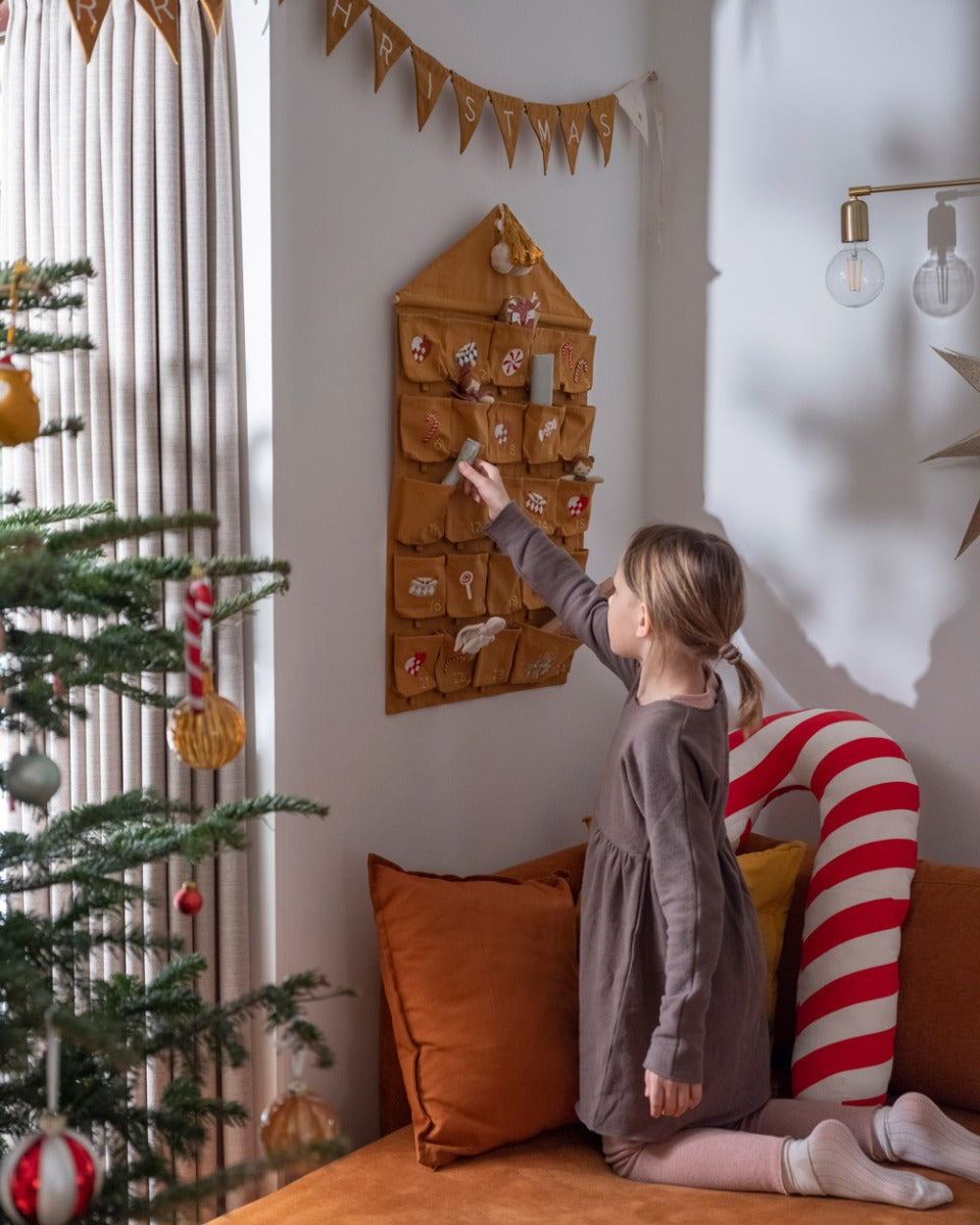 Girl on her knees pulling a toy out from the Fabelab organic cotton Christmas calendar