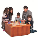 Family gathered around a small table playing the Fagus wooden enchanted playground board game on a white background