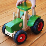 Wooden toy tractor with green and red details on a wooden floor