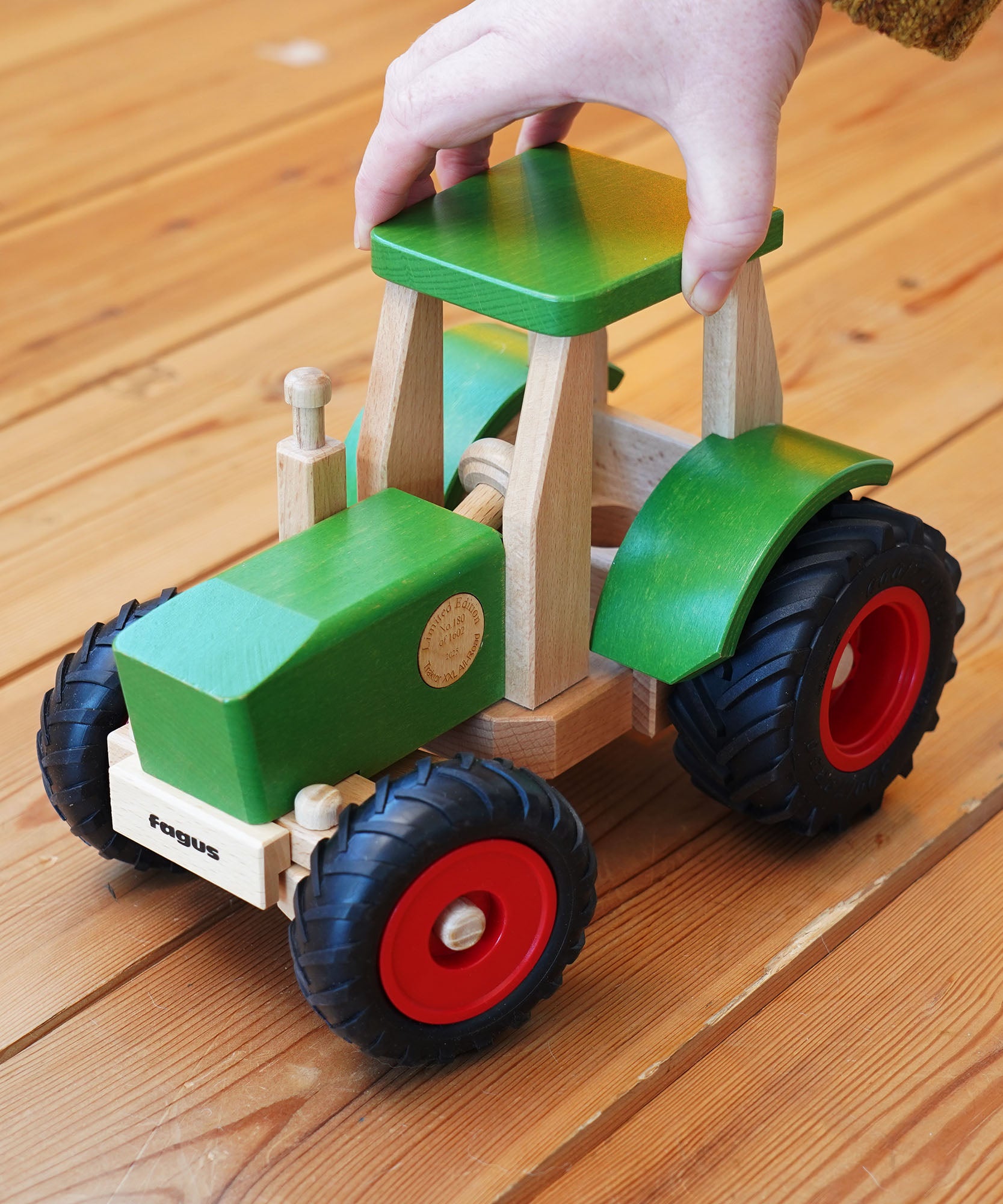 Wooden toy tractor with green and red details on a wooden floor