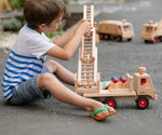 Child playing with the Fagus wooden fire engine toy, heirloom quality with an extendable rotating 3-piece ladder, rubber wheels and 6 peg doll figures. 