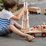 Child playing with the Fagus wooden fire engine toy, heirloom quality with an extendable rotating 3-piece ladder, rubber wheels and 6 peg doll figures. 
