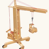 Fagus handmade wooden crane toy. The toy has four wheels on the base.
