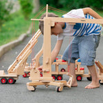 Child playing with the Fagus wooden crane toy on a concrete path