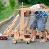 Child playing with the Fagus wooden crane toy on a concrete path