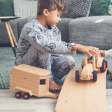 Child playing with the Fagus modern tractor and wooden horse box toy on a wooden balance board.