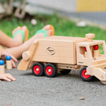 Close up of child pushing the Fagus large garbage truck toy with the sweeper attachment on the front