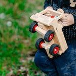 Close up of a child holding the large Fagus wooden truck toy in a grassy field