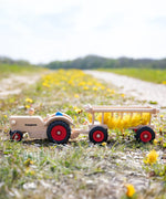 Fagus handmade wooden hay wagon toy attachment hitches onto the tractor with the trailer filled with yellow dandelions.