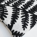 Three Etta Loves Extra Large Organic Cotton Baby Muslin Squares tied to a wooden bamboo ladder in black leopard spots