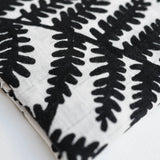 Three Etta Loves Extra Large Organic Cotton Baby Muslin Squares tied to a wooden bamboo ladder in black leopard spots