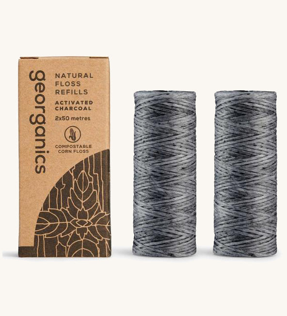 A pair of charcoal floss refills on a cream background with the cardboard box