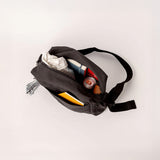 A top view of the Fluf organic cotton crossbody bag with sectioned pockets, showing items that fit inside 