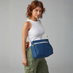 A woman wearing the organic cotton Fluf crossbody bag in navy blue with a white adjustable strap. 