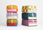 Fluf organic cotton canvas travel bags in different designs, stacked on top of each other.