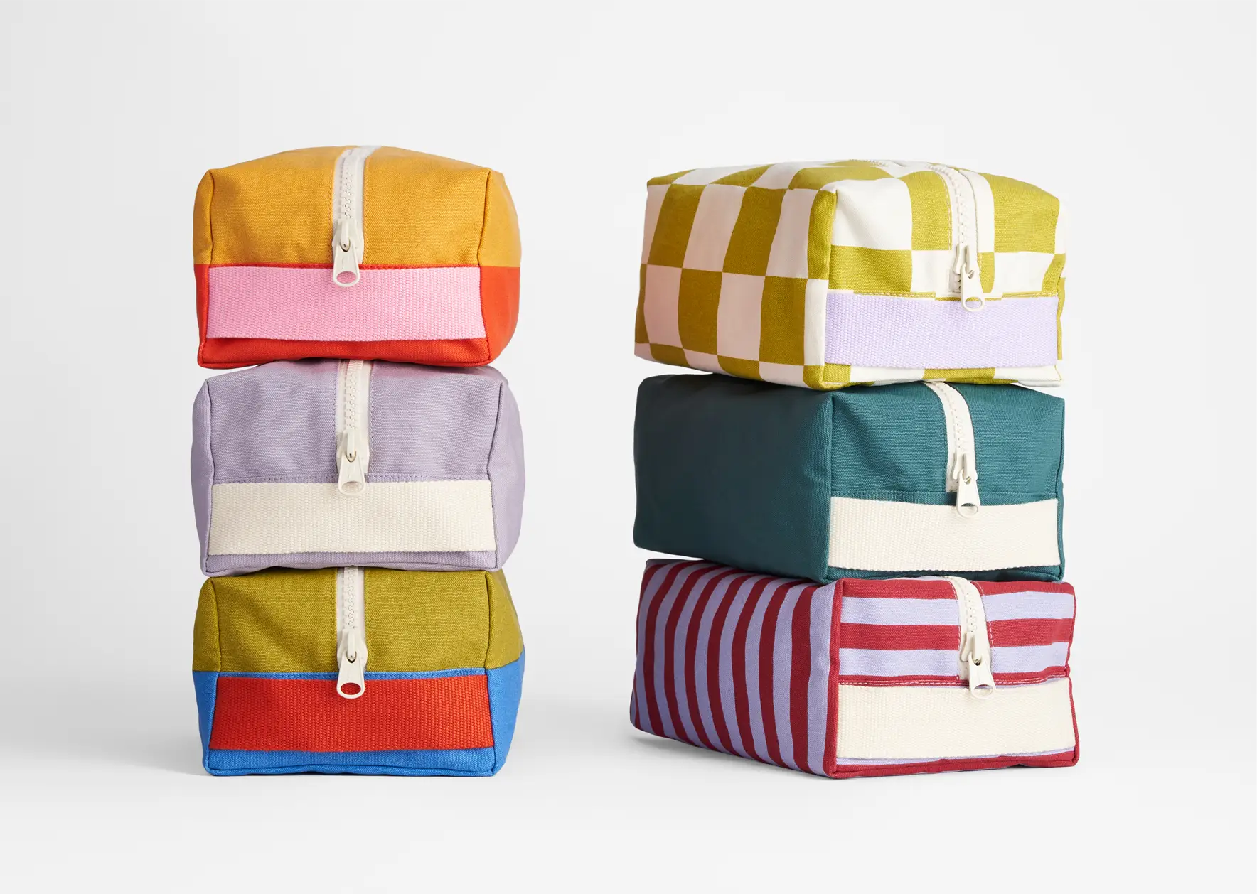 Fluf organic cotton canvas travel bags in different designs, stacked on top of each other.