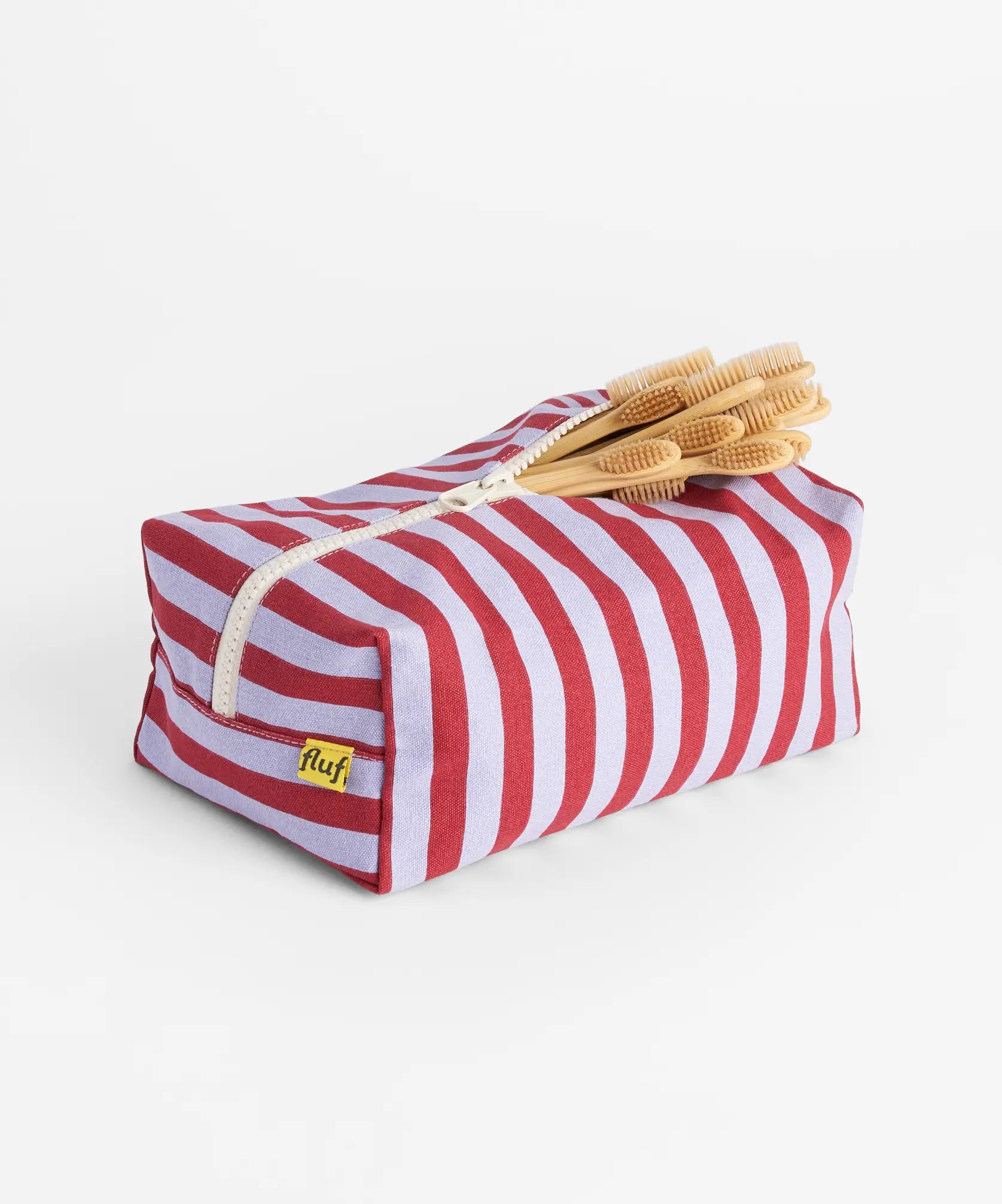 Fluf organic cotton travel washbag in Chili Stripe, with bamboo toothbrushes inside.