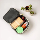 An open Fluf square lunch bag showing food and drink items inside. Lunch bag features a a rinseable, food-safe lining