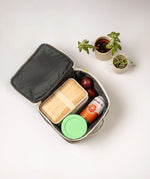 An open Fluf square lunch bag showing food and drink items inside. Lunch bag features a a rinseable, food-safe lining