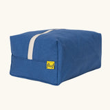 Fluf Traveller Bag in cobalt blue, a compact organic cotton washbag with orange carry handle and zip.