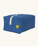 Fluf Traveller Bag in cobalt blue, a compact organic cotton washbag with orange carry handle and zip.