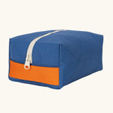 Fluf Traveller Bag in cobalt blue, a compact organic cotton washbag with orange carry handle and zip.