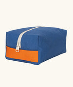 Fluf Traveller Bag in cobalt blue, a compact organic cotton washbag with orange carry handle and zip.