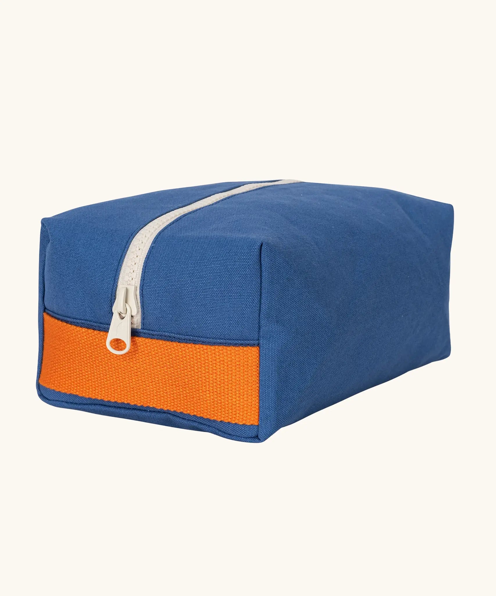 Fluf Traveller Bag in cobalt blue, a compact organic cotton washbag with orange carry handle and zip.