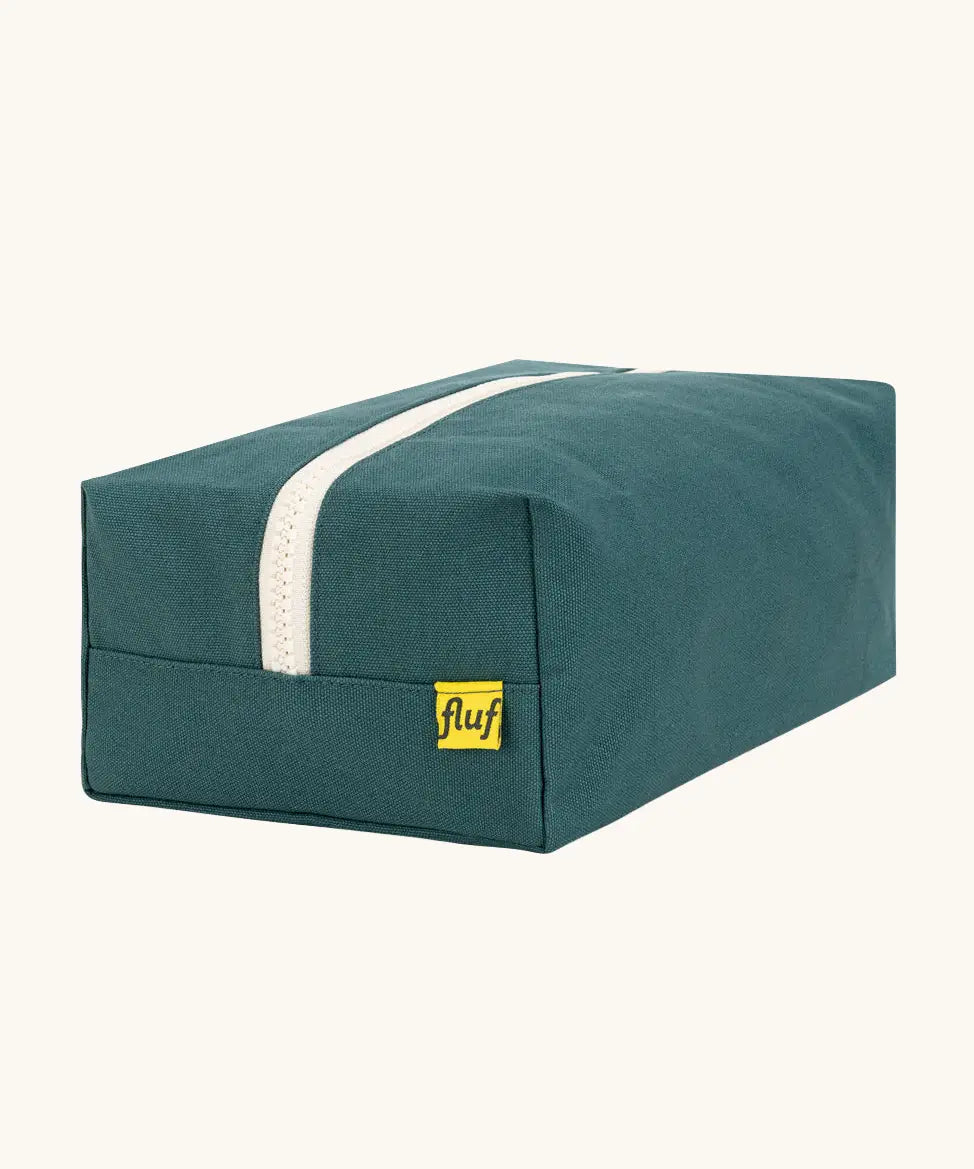Back of the Fluf Traveller Bag in cypress green, a compact organic cotton washbag with white carry handle and zip.