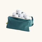 Fluf Traveller Bag in cypress green filled with golf balls, shown with zip open.